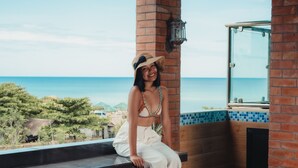 A person sitting on a wooden ledge with a view of the ocean. - The Palms Resort & Bar (San Narciso)
