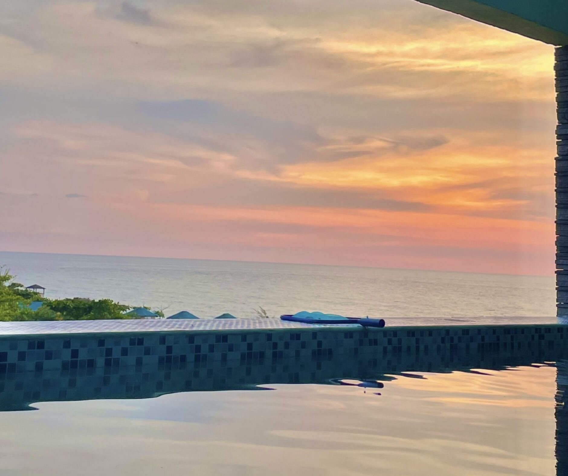 A pool with a view of the sea and a sunset.