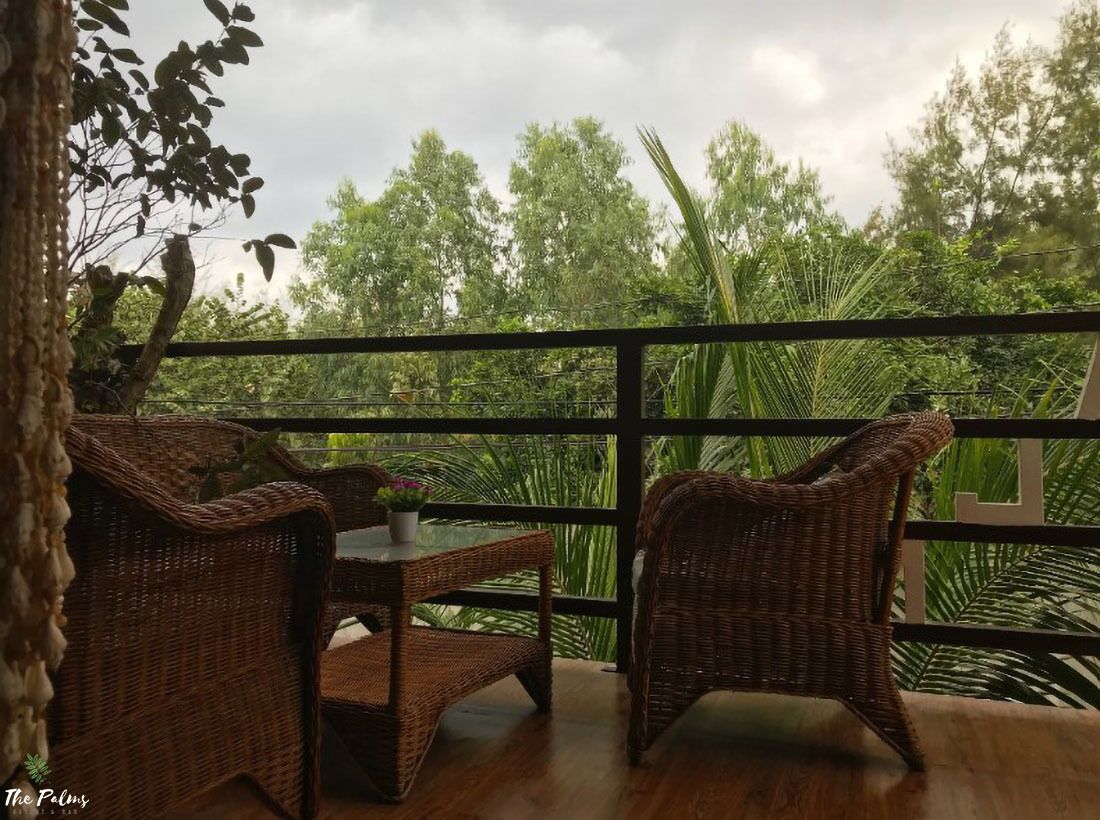 A balcony with wicker furniture and a view of lush greenery.