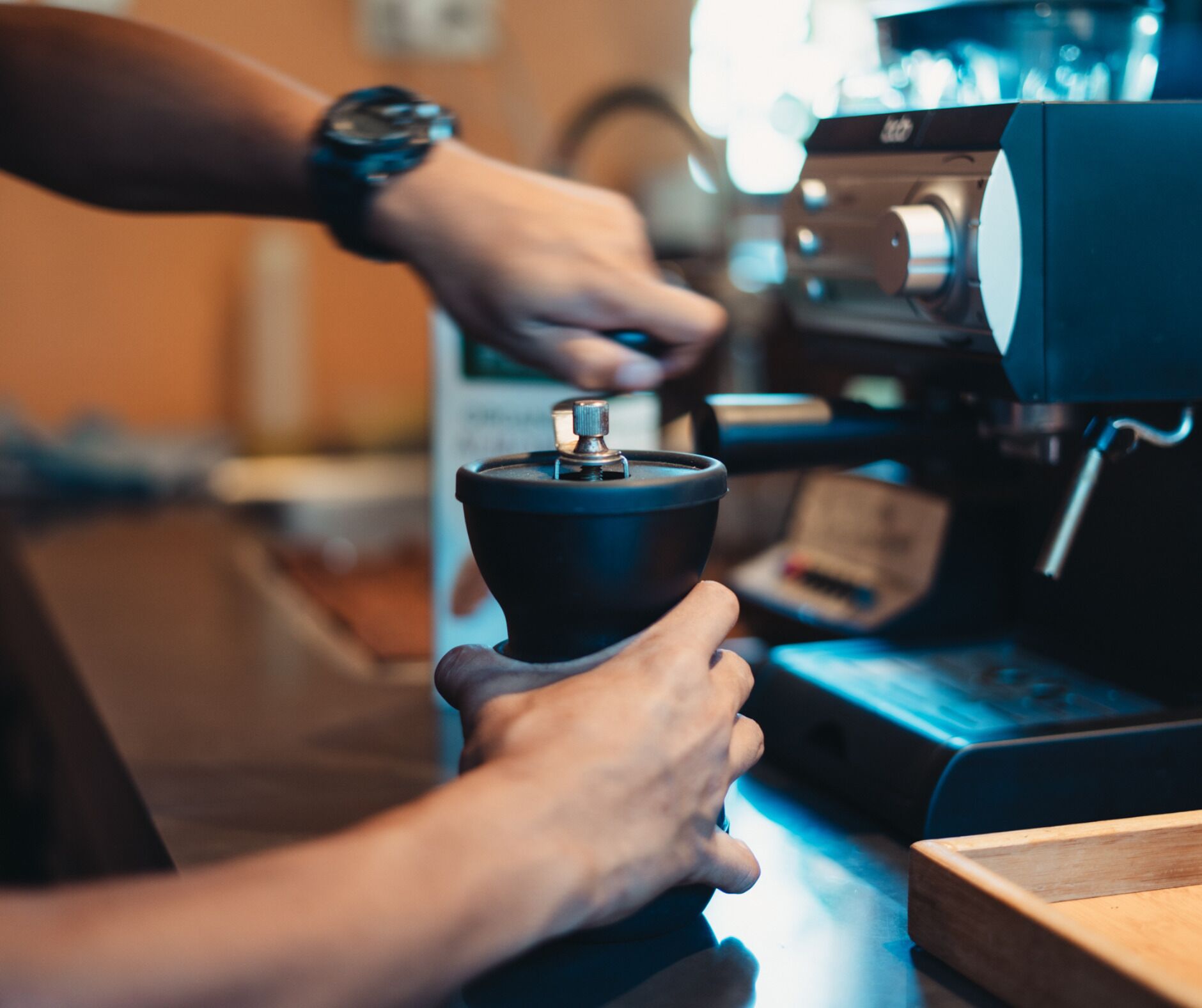 A person operating a coffee machine, likely in a cafe or restaurant setting.