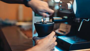 A person operating a coffee machine, likely in a cafe or restaurant setting.