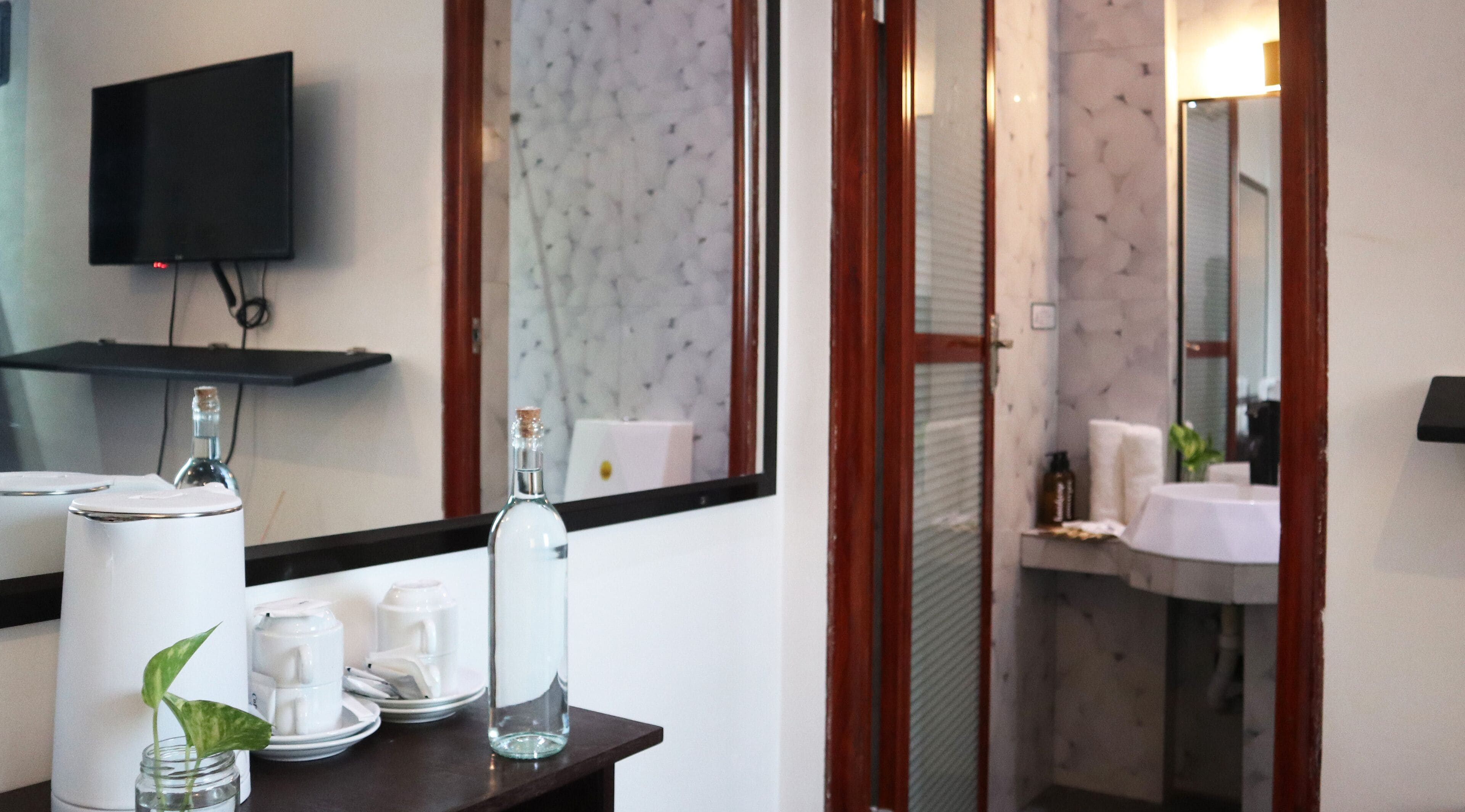 A bathroom with a sink, mirror, and a television mounted on the wall.