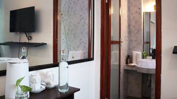 A bathroom with a sink, mirror, and a television mounted on the wall.