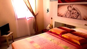 Une chambre d’hôtel avec un lit, un téléviseur posé sur une table de chevet et un tableau accroché au mur.