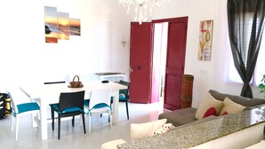 Un salon moderne avec un canapé blanc, une table à manger et des chaises, et une porte rouge.
