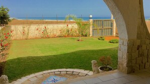 Un espace patio offrant une vue sur l’océan, un mur en pierre et un petit jardin agrémenté d’un décor de carreaux.