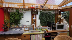 A cozy kitchen with a wooden countertop, a microwave, and a sink. There are wicker chairs and a potted plant. - Wockninsee - Finnish log house & round log house (Ückeritz)