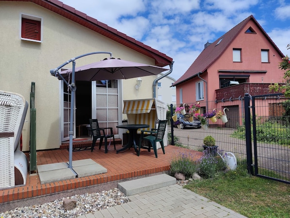 A patio with a table and chairs, a covered area with an umbrella, and a garden with potted plants.