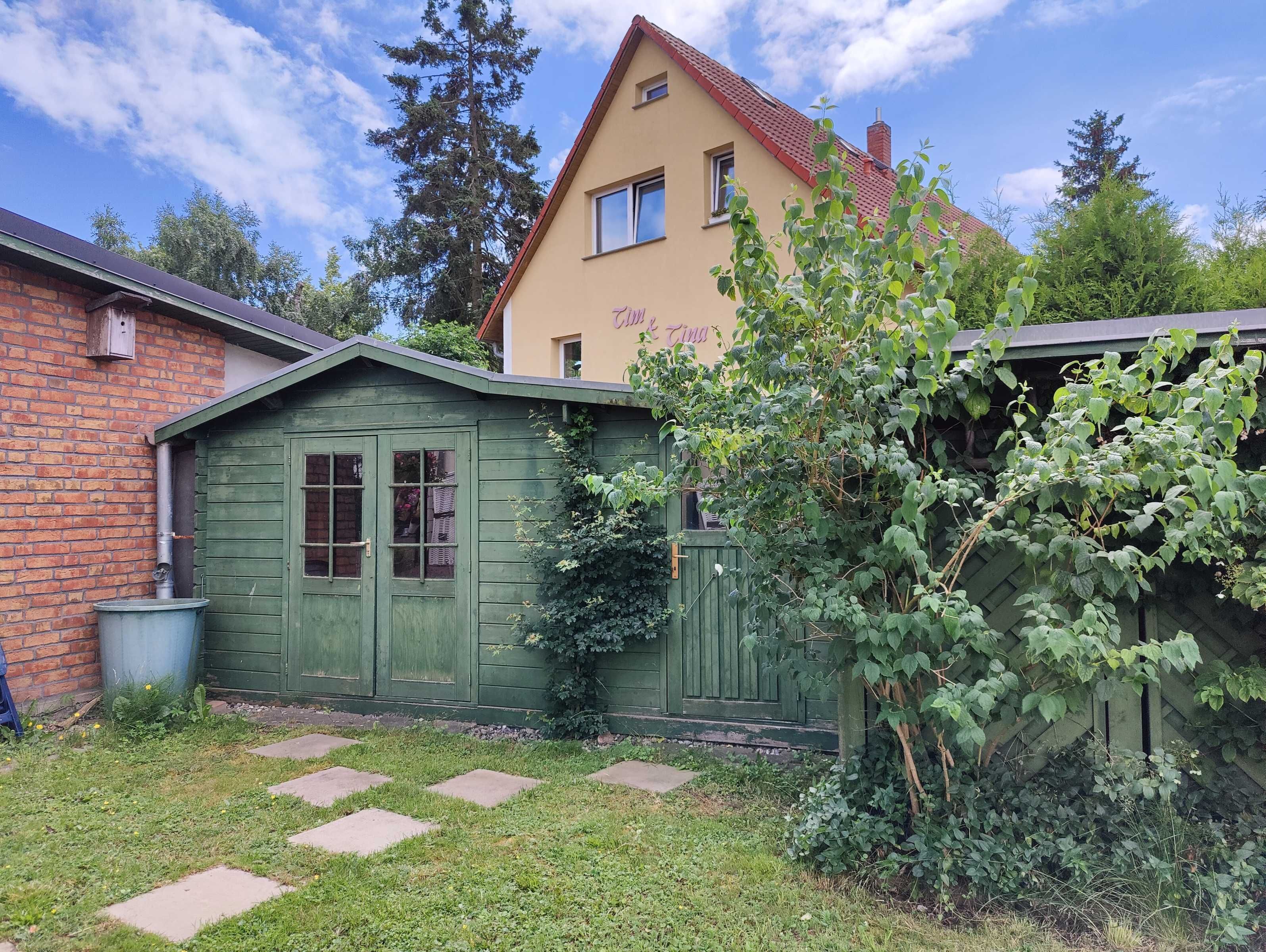 A two-story building with a green wooden shed and a brick wall.