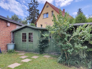 A two-story building with a green wooden shed and a brick wall.