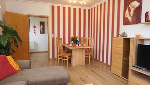 Un salon comprenant un canapé, une table à manger avec des chaises, un meuble pour la télévision et un mur à rayures.