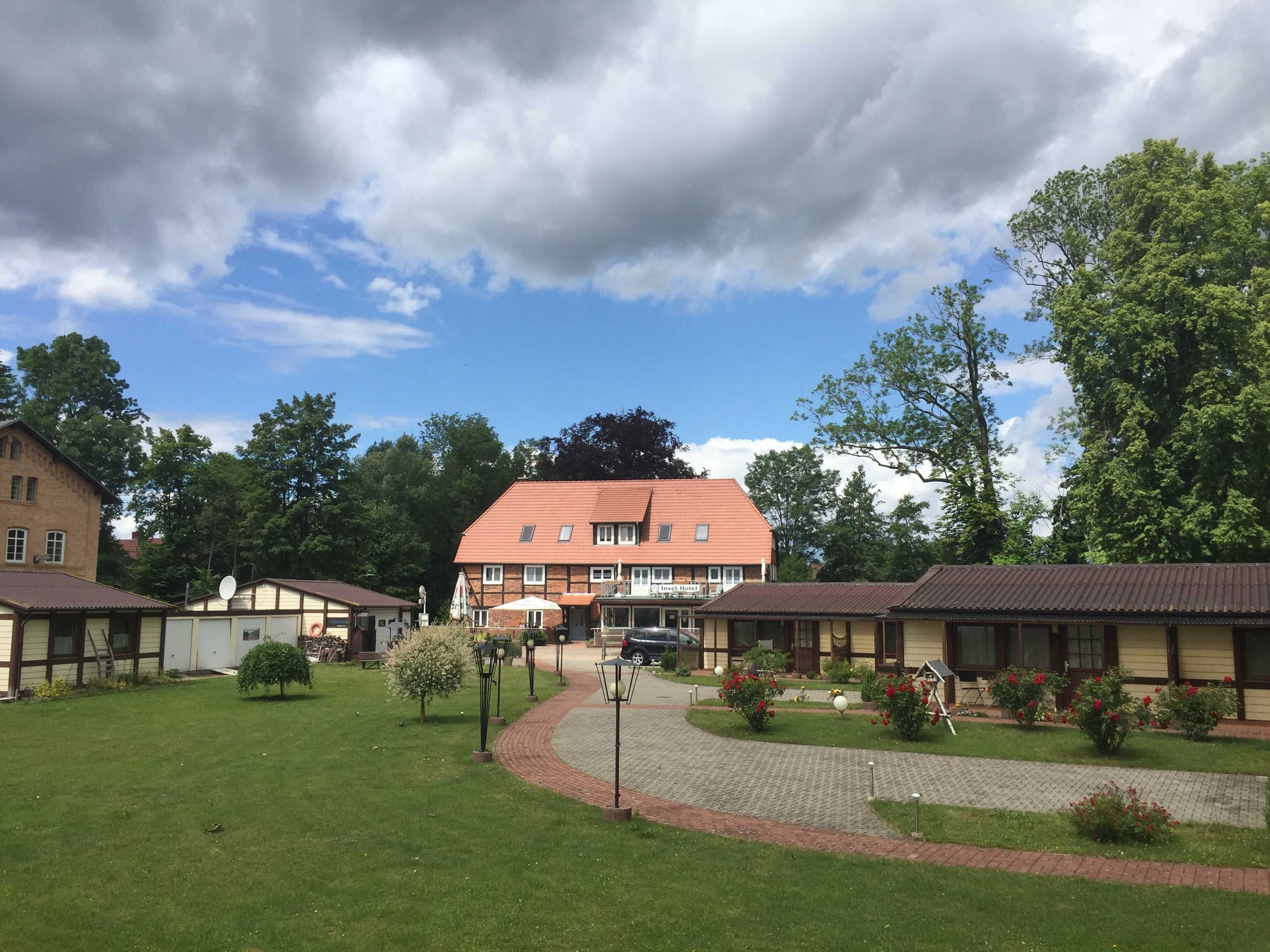 A traditional building with a red roof, surrounded by well-maintained lawns and small trees.