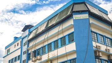 A multi-story hotel with blue and white exterior walls, air conditioning units, and a sign indicating it is the Valai hotel.