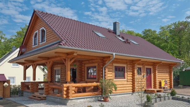 A log cabin with a red-tiled roof, a porch, and a chimney.