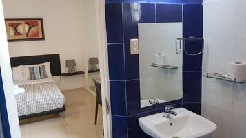 Une salle de bain moderne avec un grand miroir, un lavabo blanc et un espace douche.