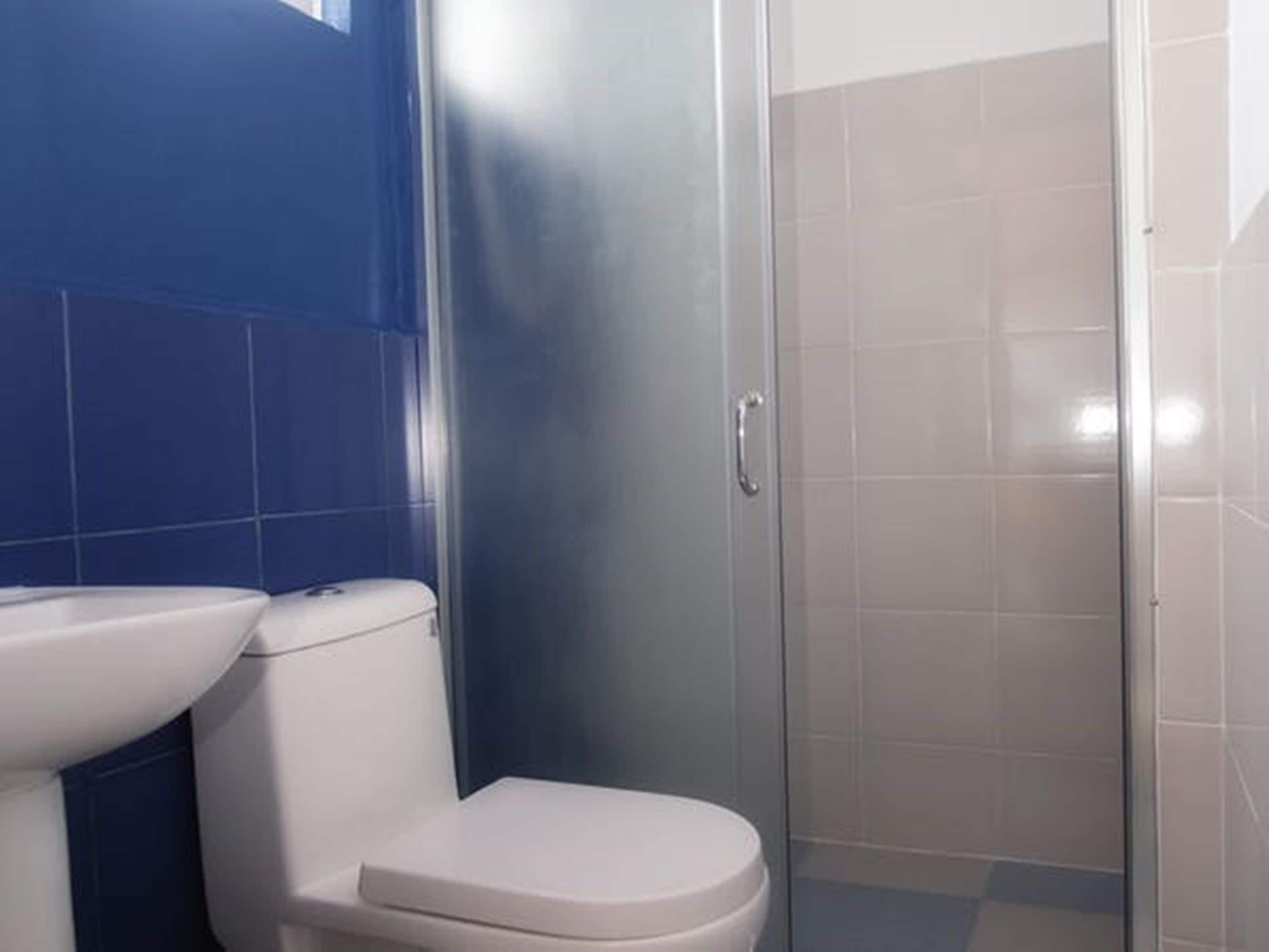 Un baño con inodoro, lavamanos y cabina de ducha.