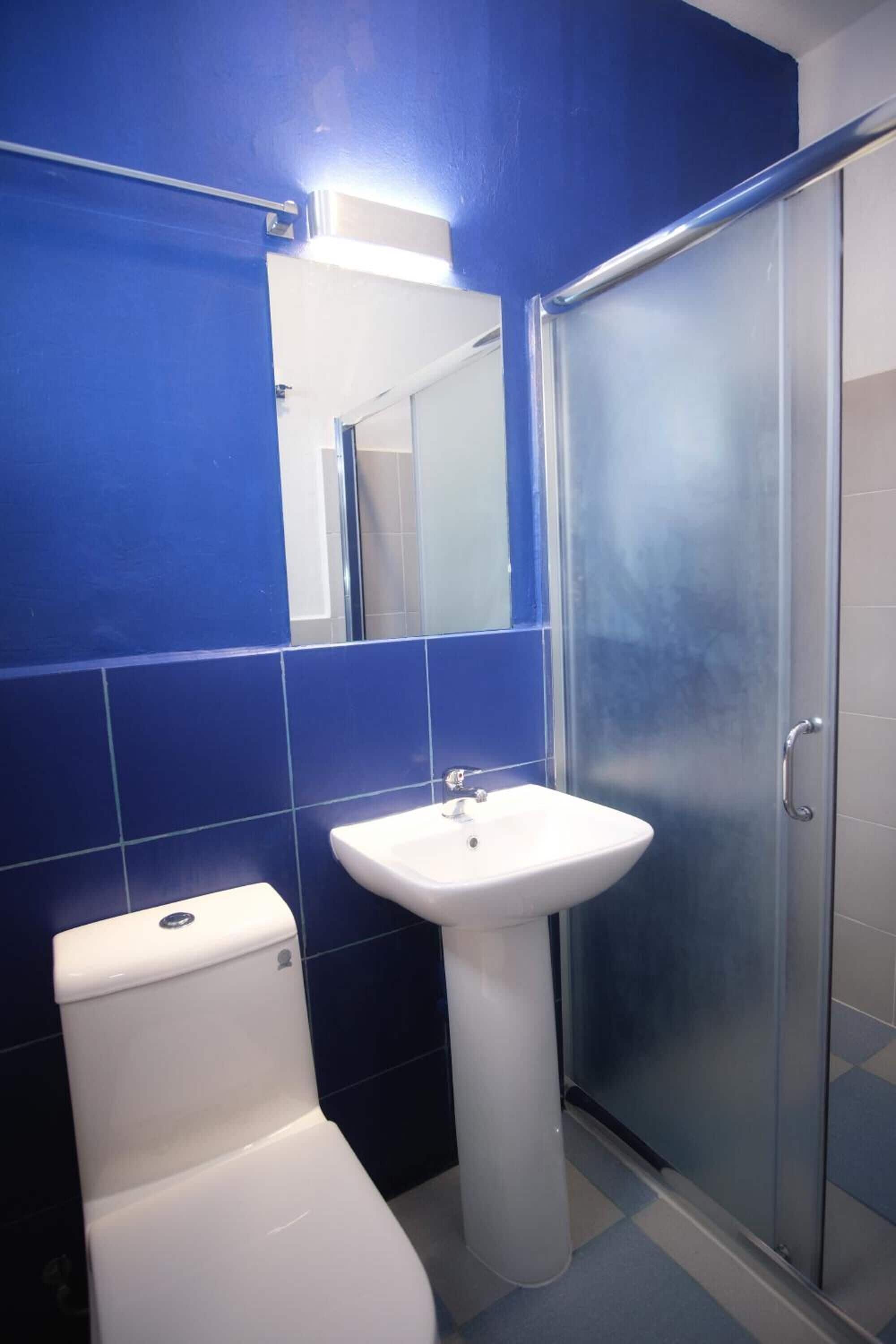 A bathroom with a white toilet, a pedestal sink, and a glass shower enclosure.