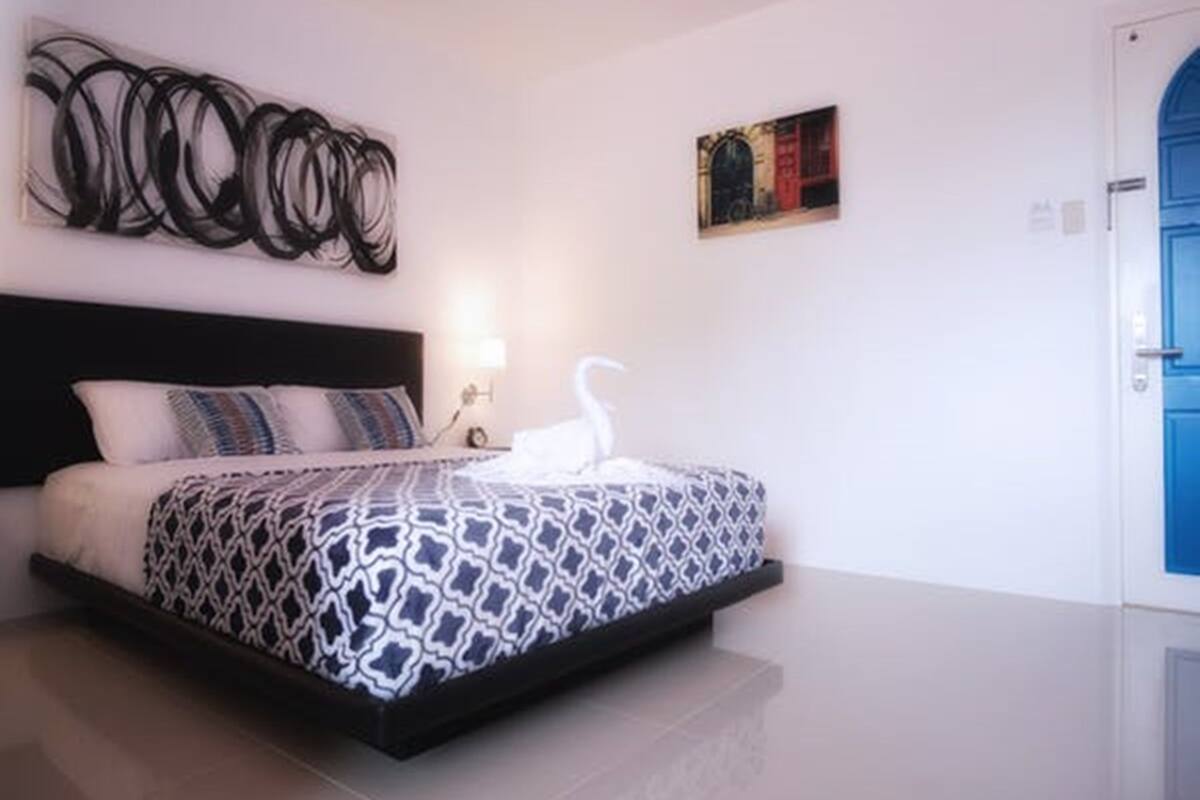 A bedroom with a bed, a wall art piece, and a door.