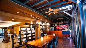 A spacious library with wooden floors and bookshelves, a long table with chairs, and a ceiling fan. - Shin Kong Chao Feng Ranch And Resort (Fenglin)