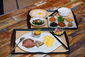 A tray with various breakfast items including eggs, sausages, and scrambled eggs on a wooden table. - Shin Kong Chao Feng Ranch And Resort (Fenglin)