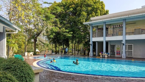 Zona de piscina amb una zona de seients coberta i un edifici amb balcó.