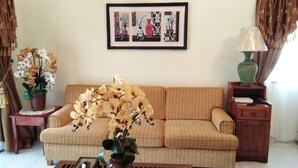 Un saló amb un sofà, una taula de centre, una obra d'art emmarcada a la paret, una làmpada i una planta en test.