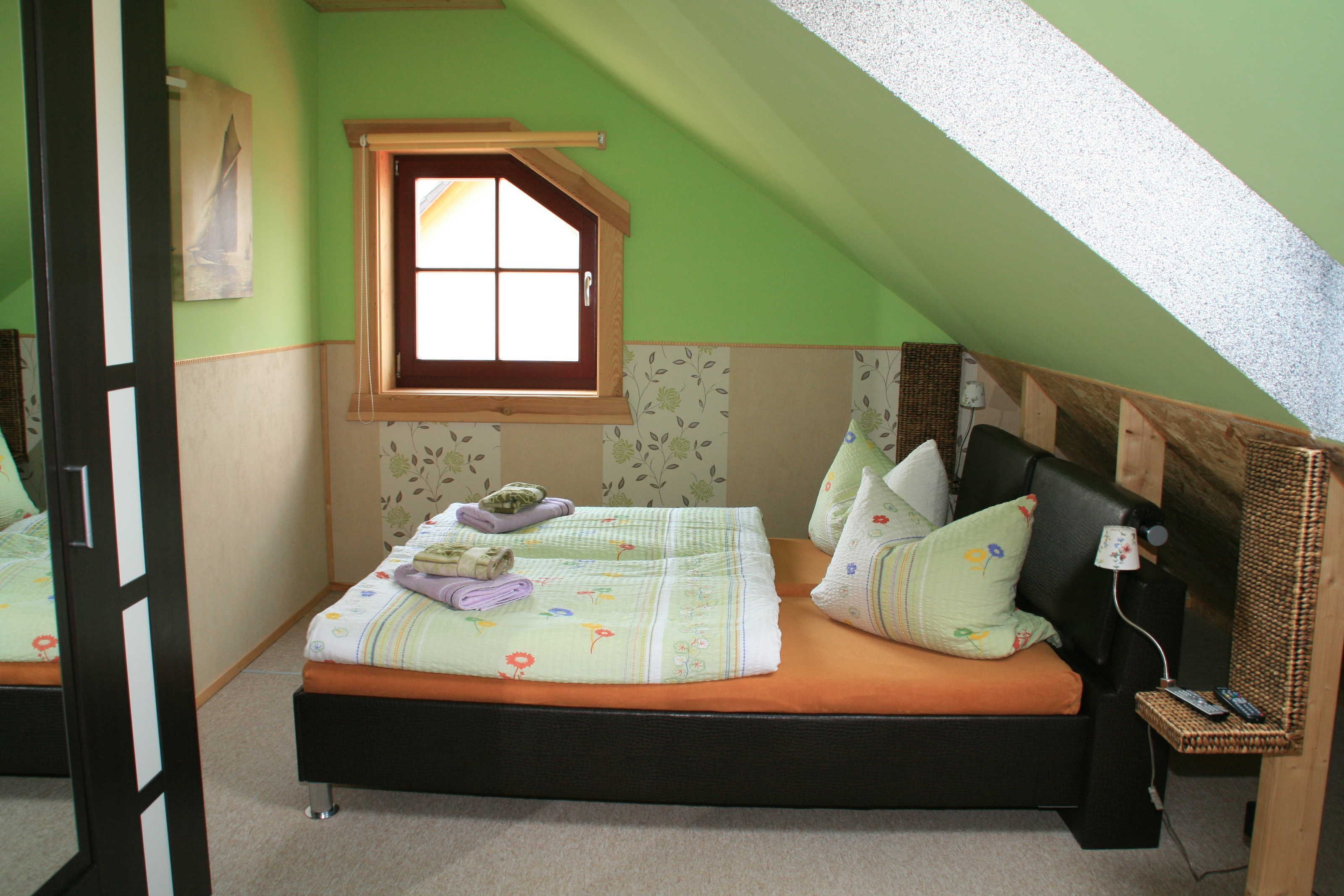 A bedroom with a bed, a window, a lamp, and a small table.