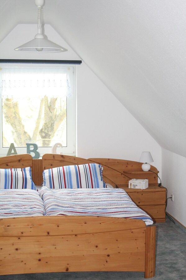 Une chambre à coucher avec un lit en bois, une table de chevet, une lampe et une fenêtre ornée des lettres « A », «  B » et « C ».