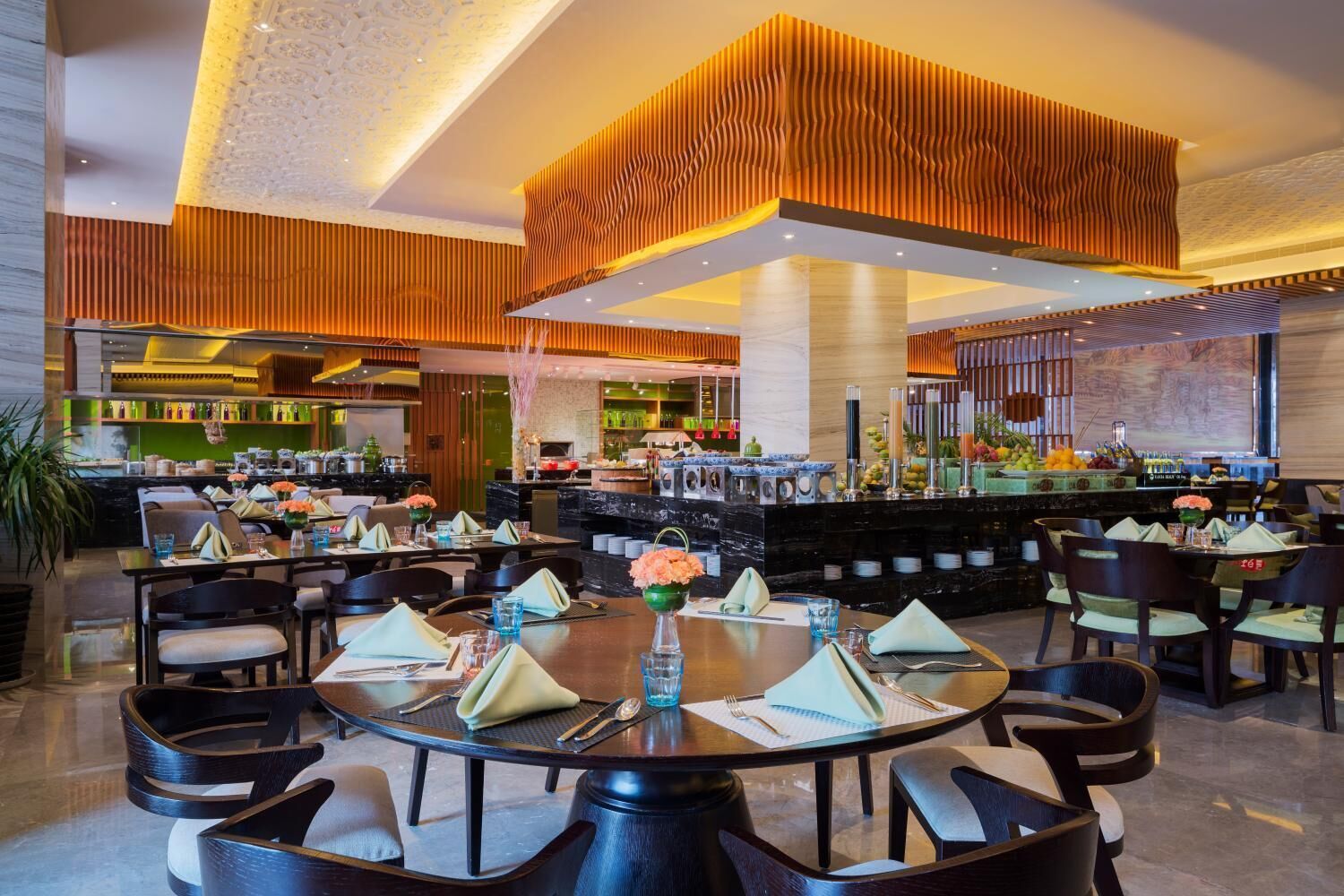 Un restaurante moderno con mesas redondas, sillas negras y una zona de bar central.