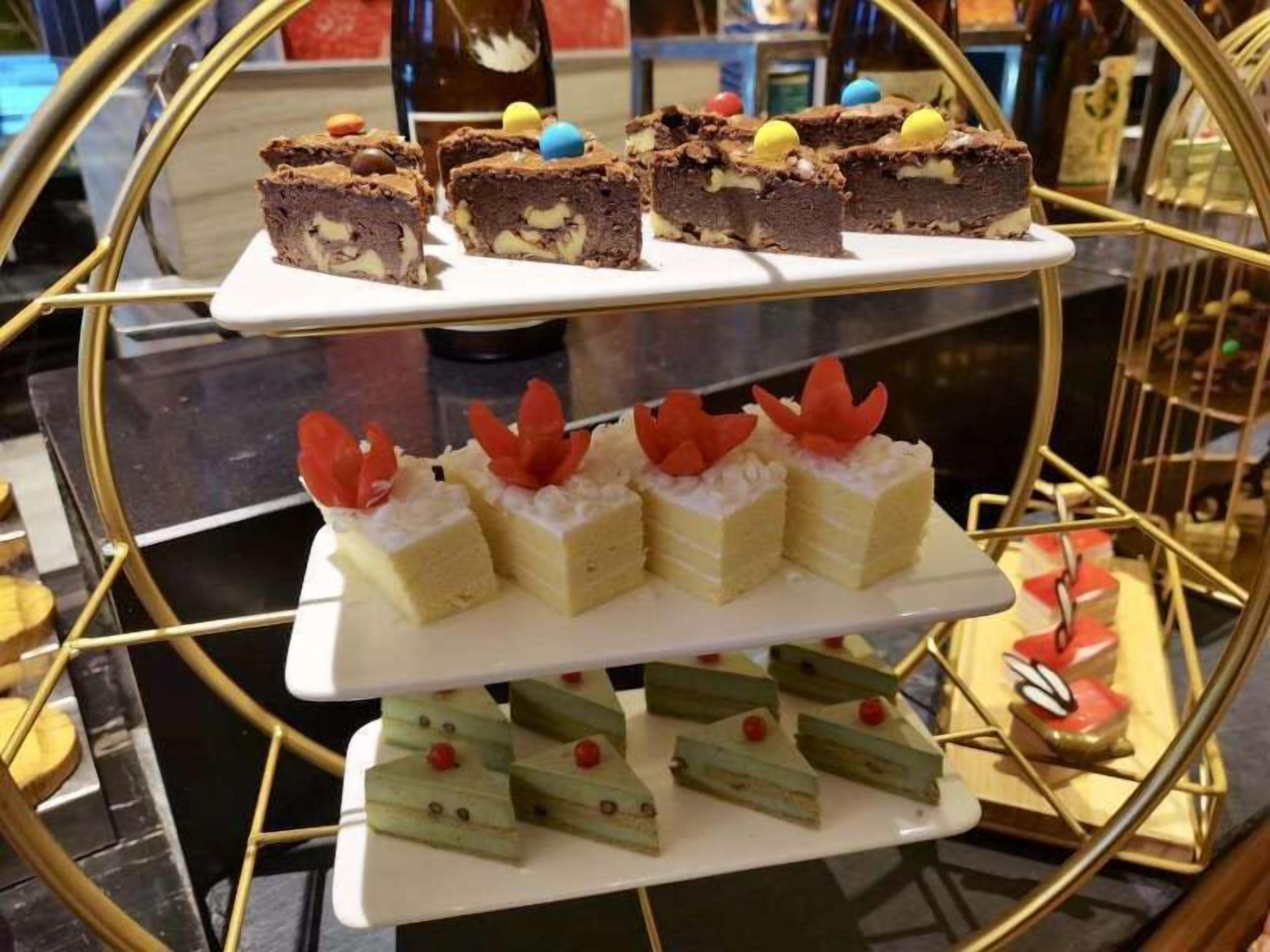 A dessert display with various types of cakes and pastries on a multi-tiered stand.