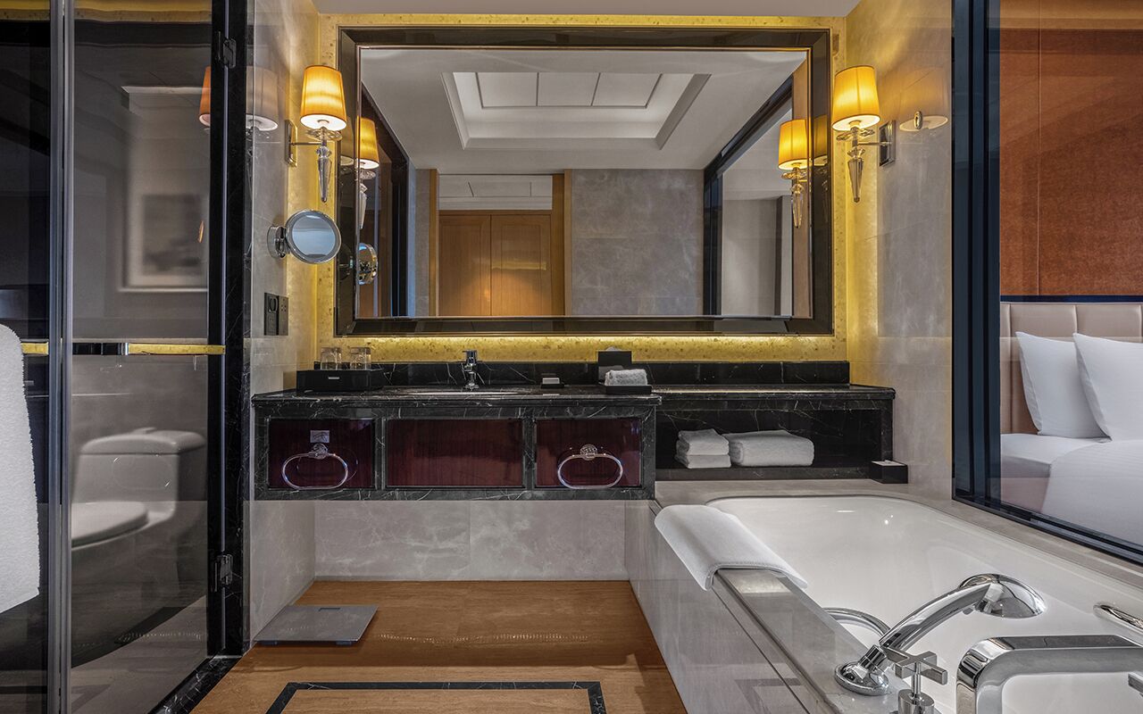 Un bagno moderno con un grande specchio, due lavabi, una vasca e un box doccia in vetro.