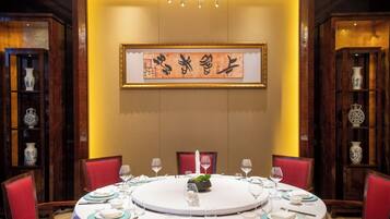 Mesa redonda para seis personas, con sillas rojas, una araña y arte de caligrafía china tradicional en la pared.