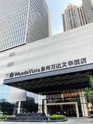 Un edificio moderno con un llamativo letrero WandaVista, amplias ventanas y fachada reflectante.