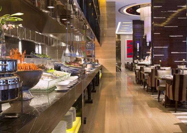 A buffet area with various food items and a seating area with tables and chairs. - Wanda Vista Quanzhou (Quanzhou)