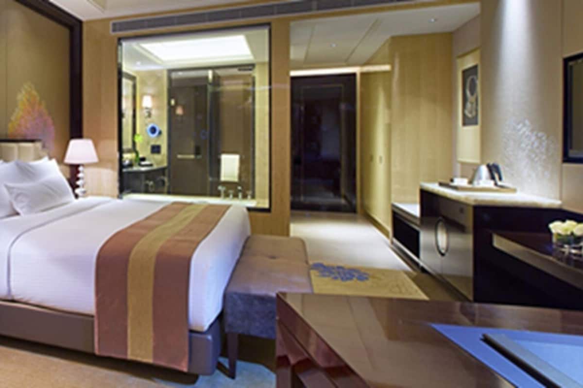 A hotel room with a bed, two bedside tables, a chair, a desk, and a mirror.