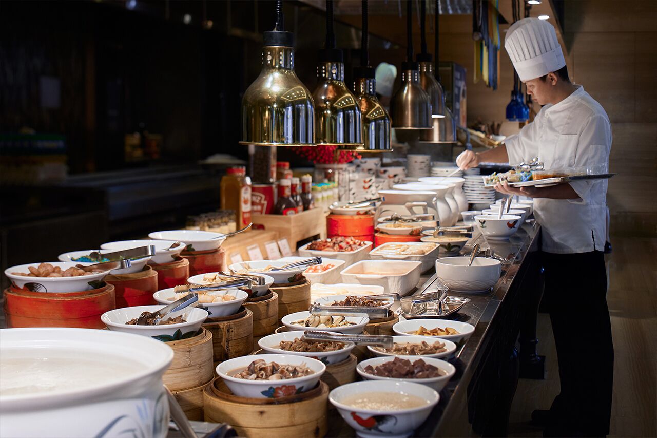 A buffet setup with various food items and a chef serving.