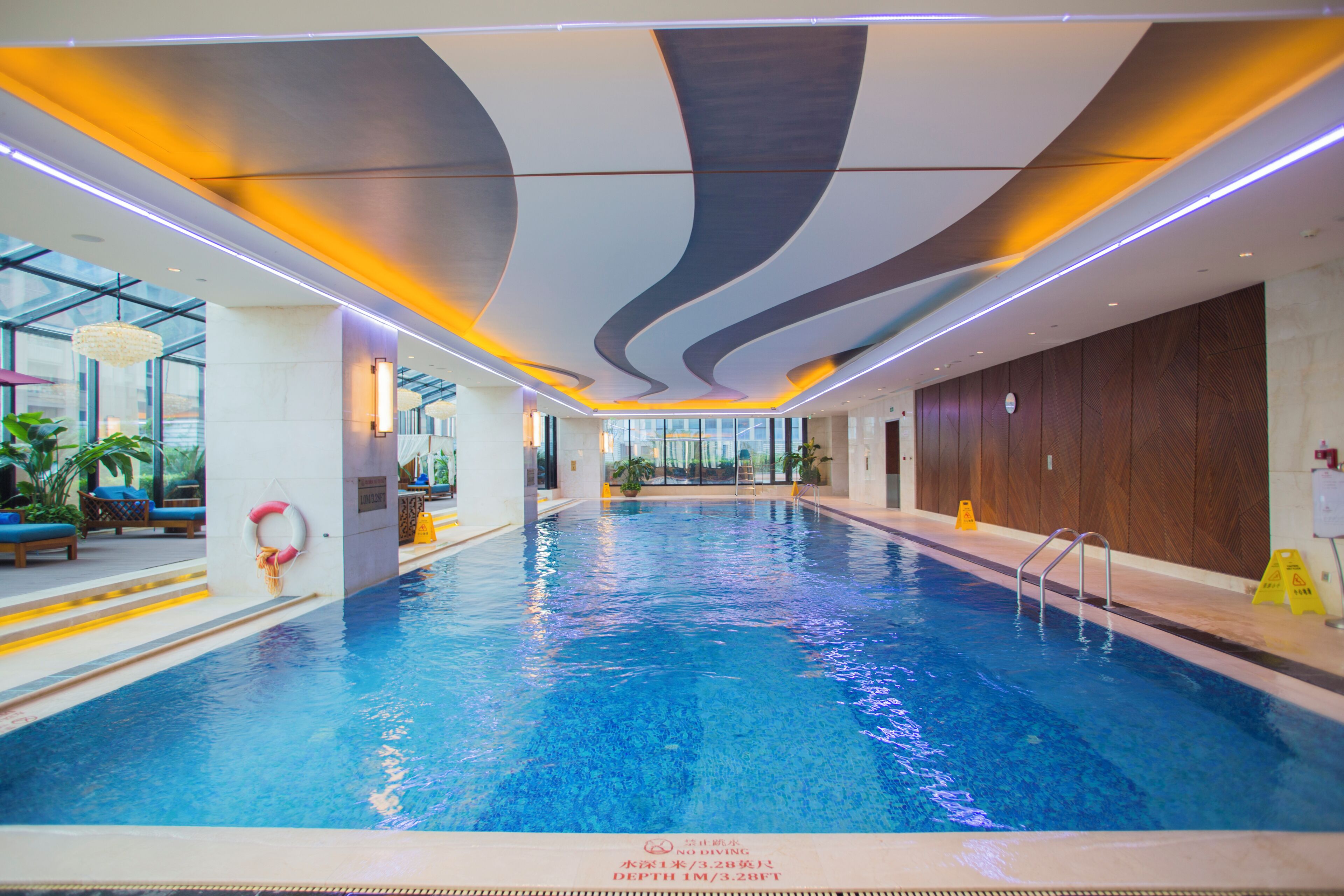 Ein Innenpool mit klarem Wasser, umgeben von einem modernen Innenraum mit gewölbter Decke und heller Beleuchtung.