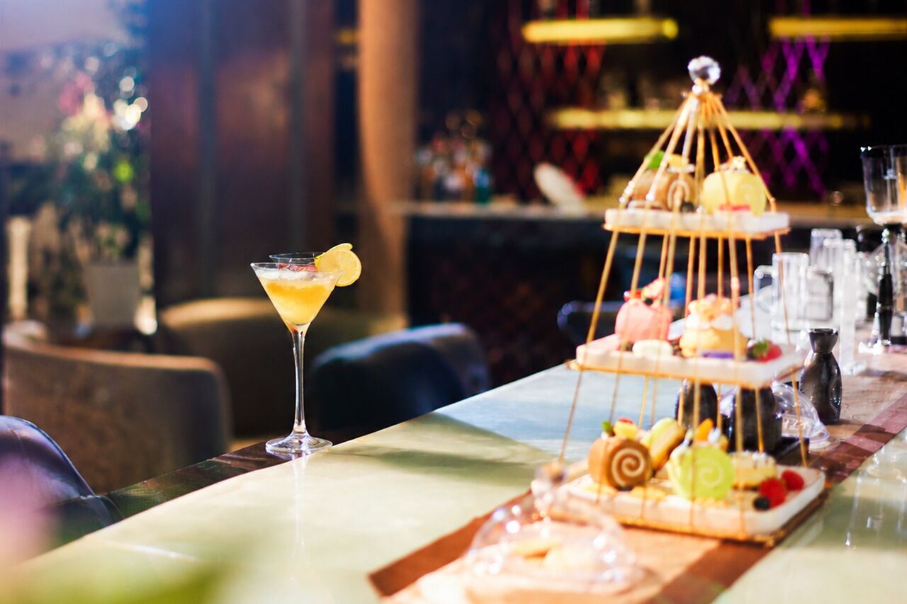 Un bar con una copa de martini y un pastel de varios niveles.
