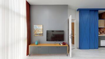 A modern living room with a grey wall, a flat-screen TV, a wooden console table, and a painting.