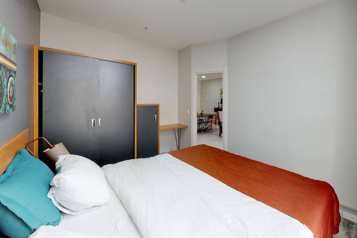 A hotel room with a bed, a wardrobe, a desk, and a chair.