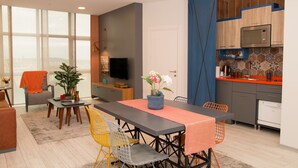 A modern kitchen with a microwave, oven, and sink. There is a dining area with a table and chairs, and a living room with a sofa and a TV. - ZİN D Home Dudullu Suit Otel (Istanbul)