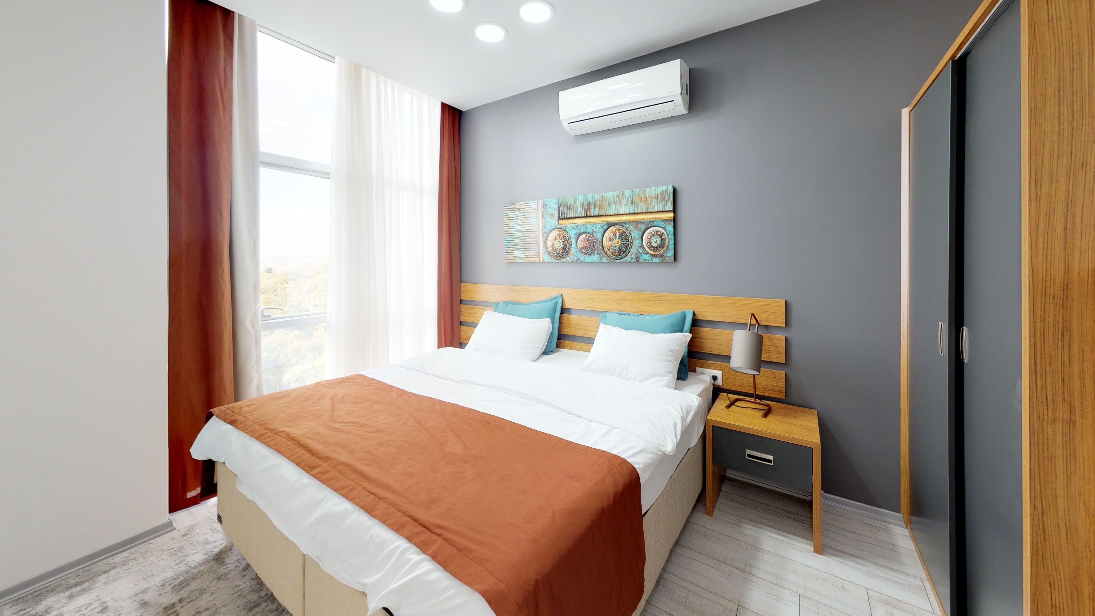 A modern bedroom with a bed, nightstands, a wardrobe, and an air conditioning unit.