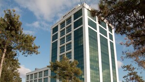 A modern multi-story building with a glass facade, surrounded by trees. - ZİN D Home Dudullu Suit Otel (Istanbul)