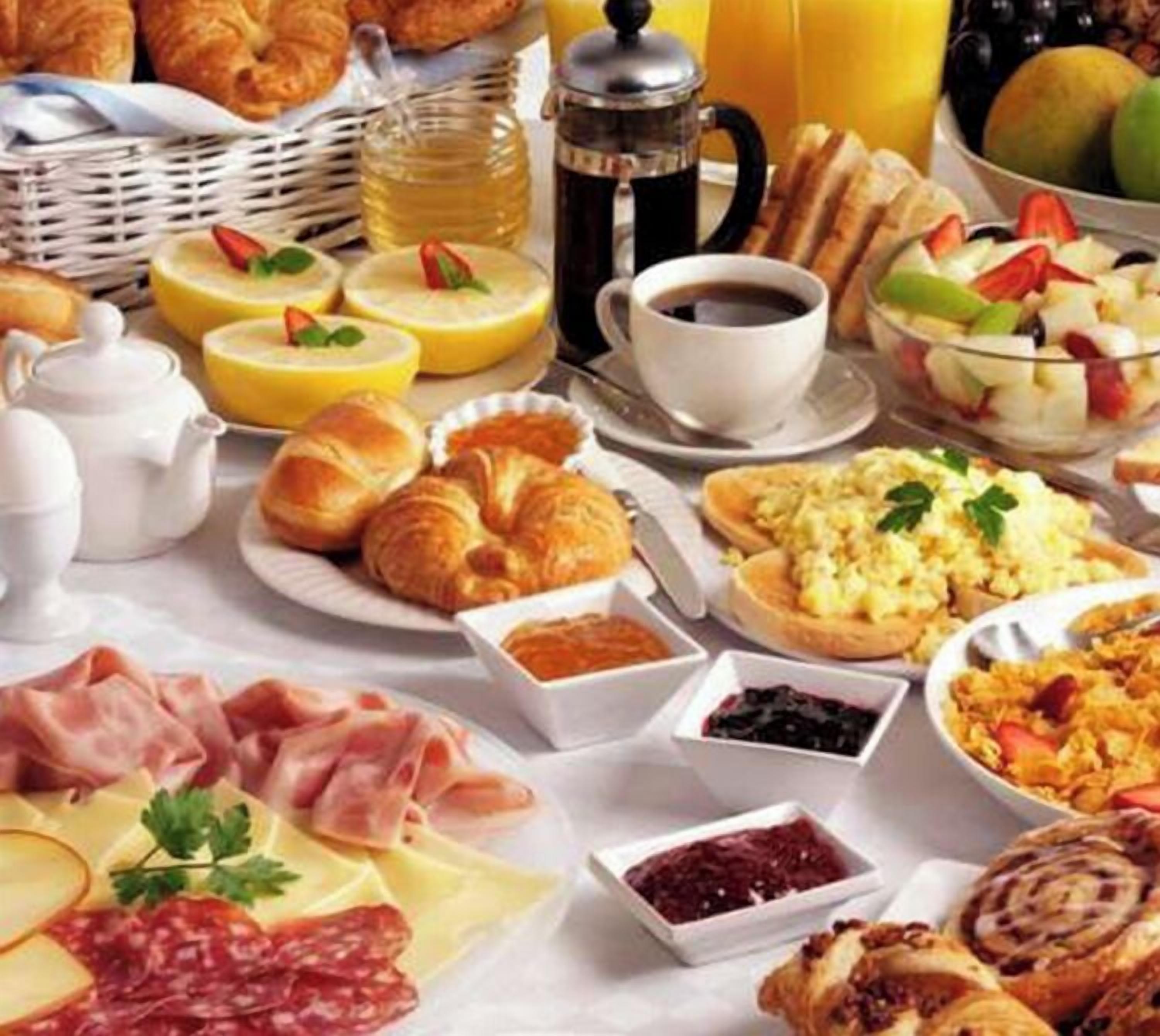 Ein Frühstücksbuffet mit einer Auswahl an Speisen, darunter Gebäck, Fleisch und Obst.