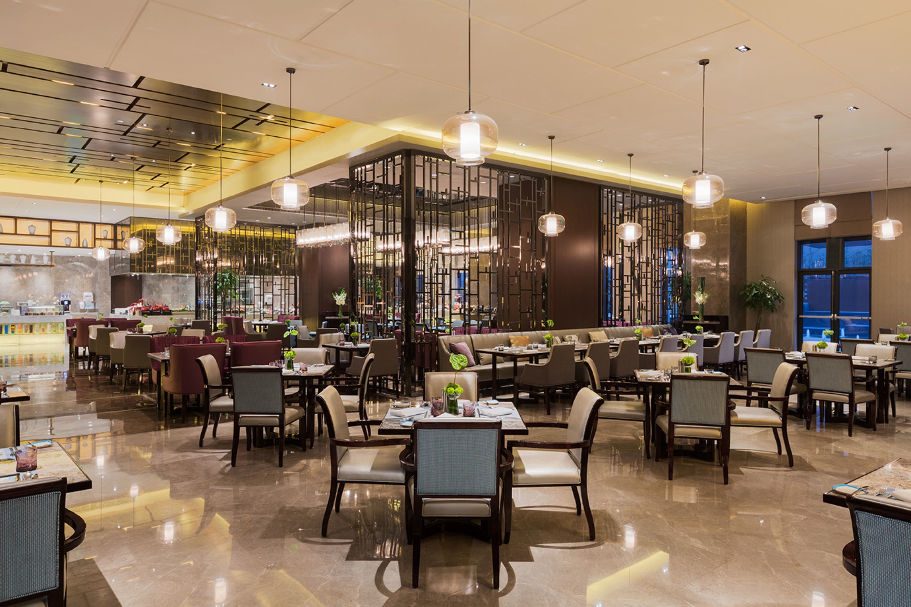A spacious restaurant with high ceilings, modern pendant lighting, and a variety of seating arrangements including tables and booths.