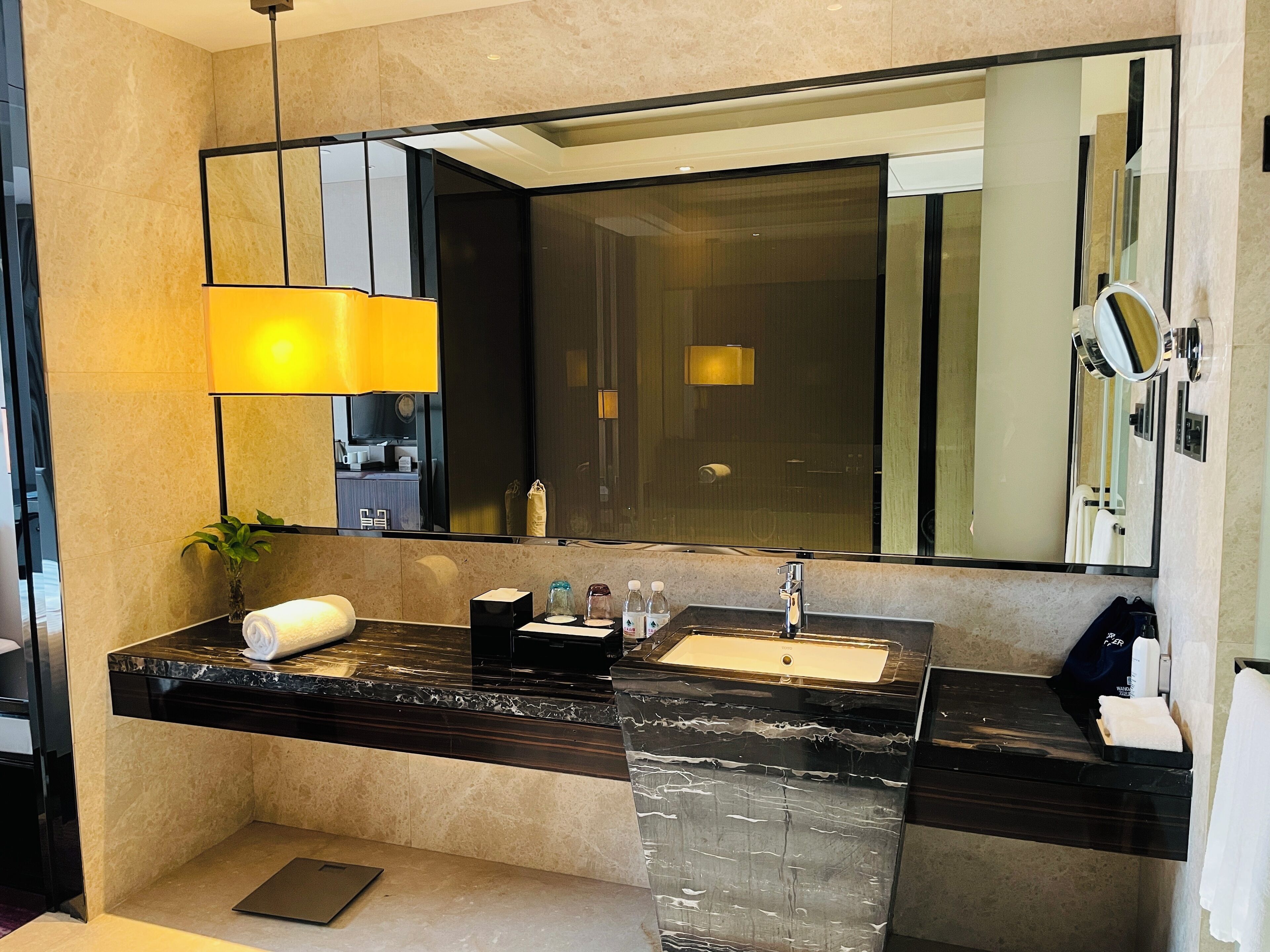A modern bathroom with a black marble countertop, a large mirror, a sink, and a towel rack.