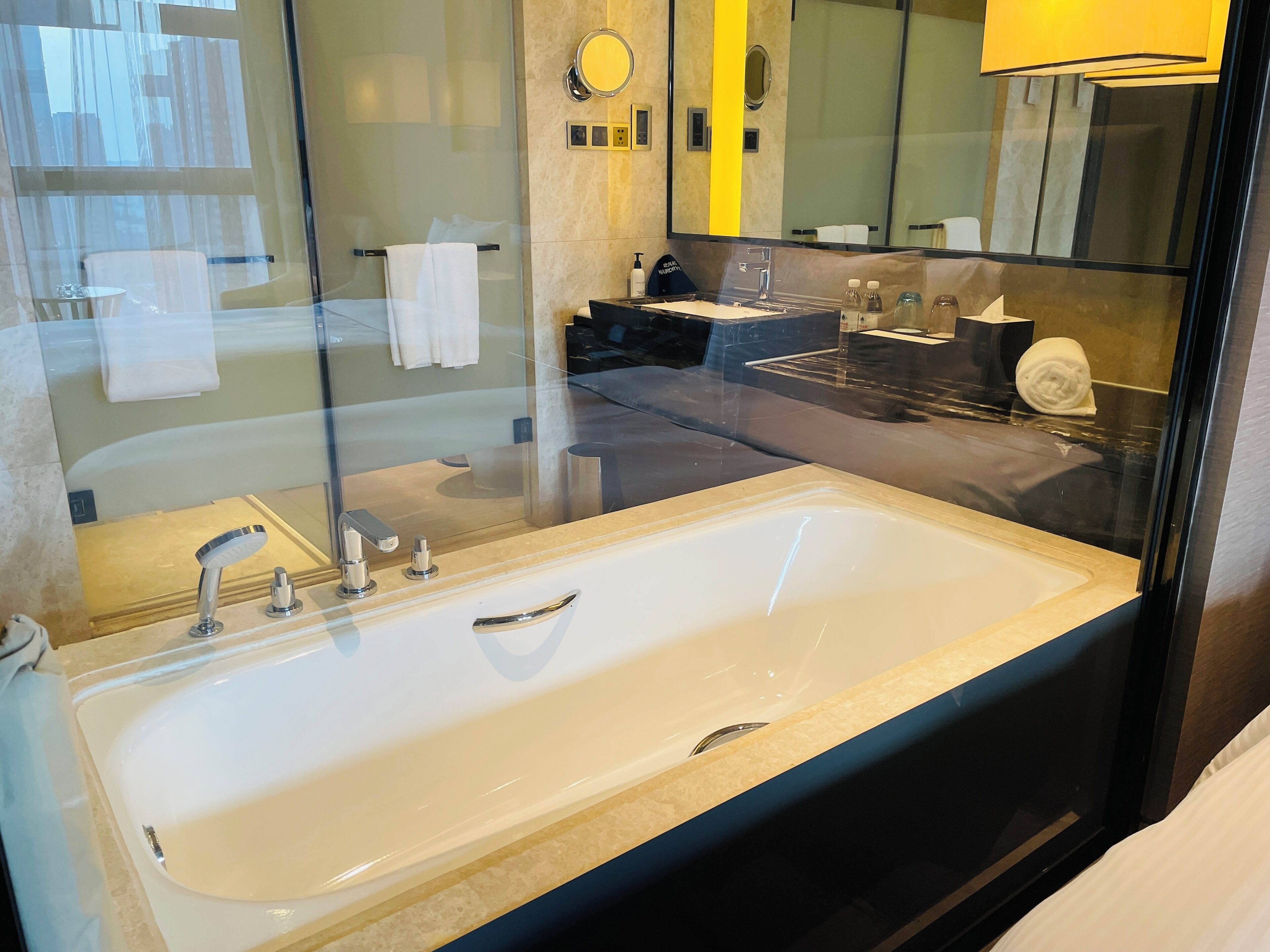 Un baño moderno con una bañera grande, zona de ducha con mampara de vidrio y tocador con lavabo y espejo.