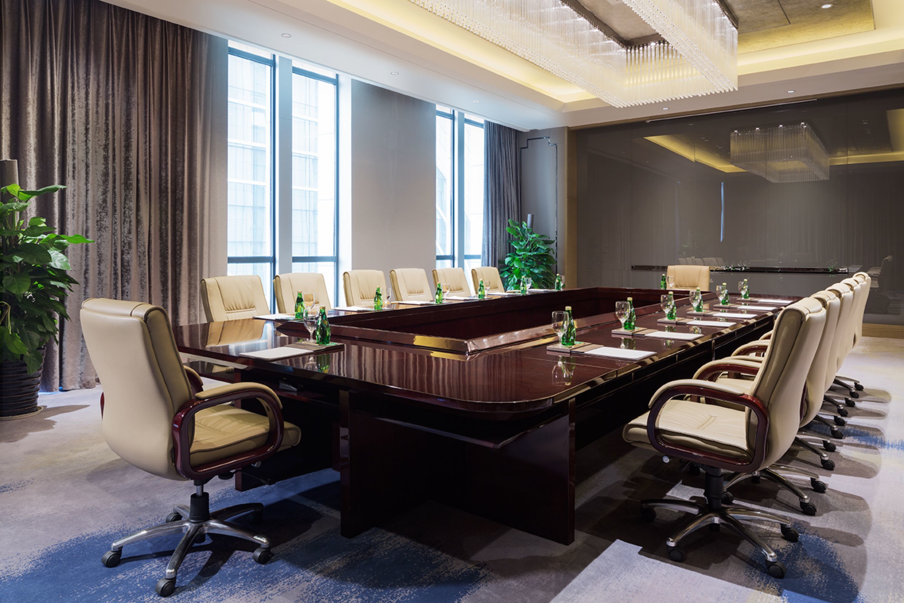 A conference room with a long table, multiple chairs, and a large screen.