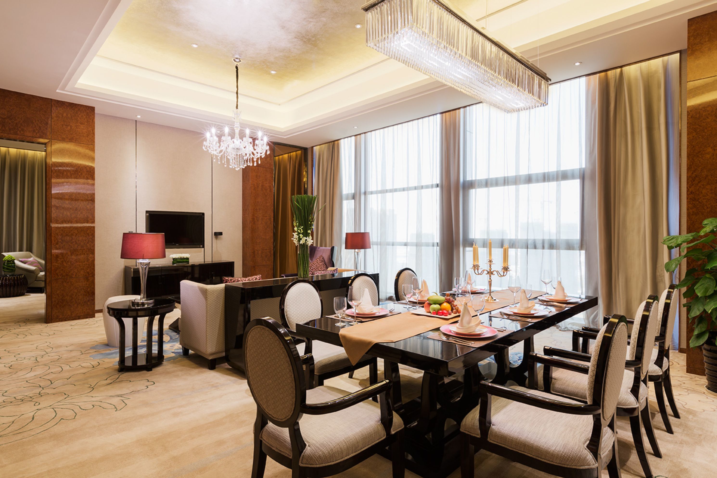 A spacious dining area with a long table, multiple chairs, and a chandelier.