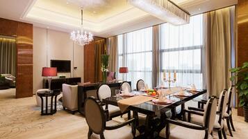 A spacious dining area with a long table, multiple chairs, and a chandelier.